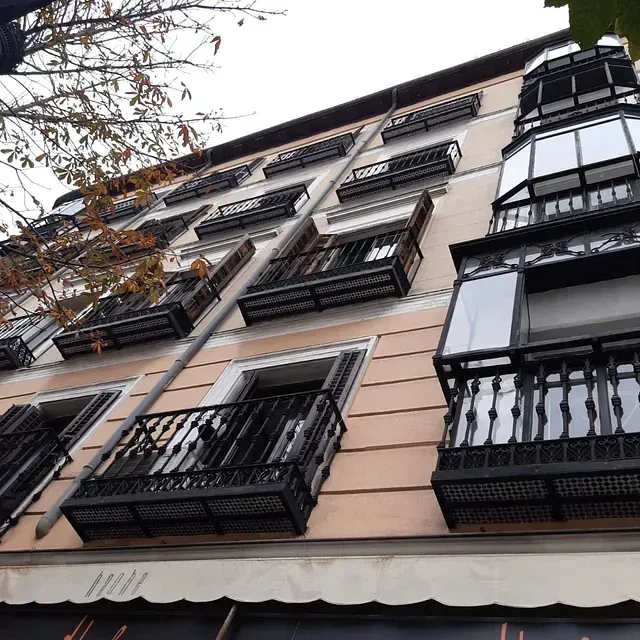 Mirando hacia arriba a un edificio con balcones y un cartel que dice 'a' en él