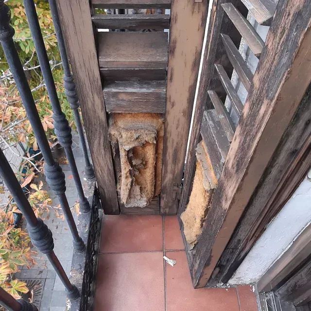 Un balcón con una escalera de madera que conduce a él.