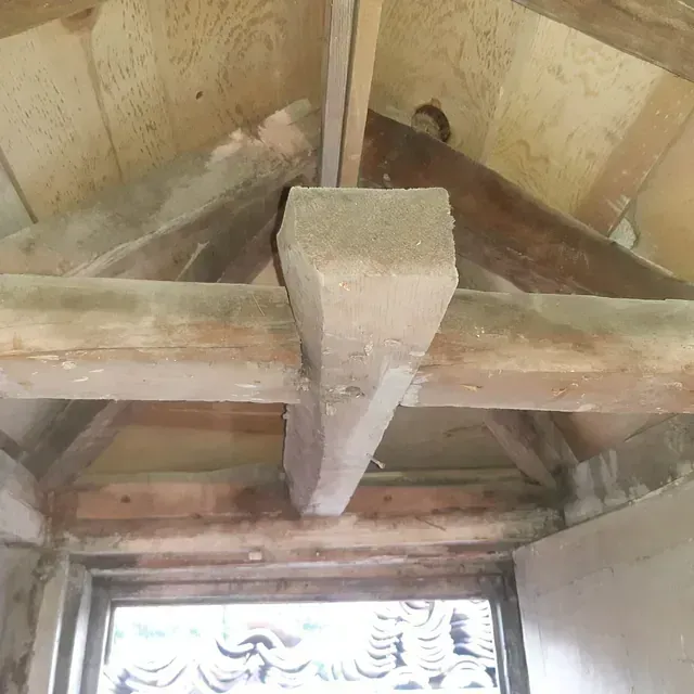 Una viga de madera cuelga del techo de una habitación al lado de una ventana.