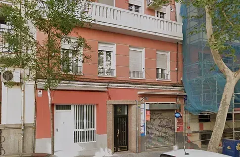 Un edificio rojo con un coche blanco aparcado delante.