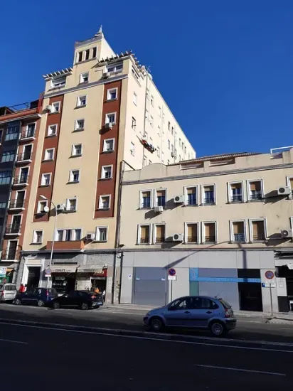 Un coche está aparcado delante de un edificio alto.