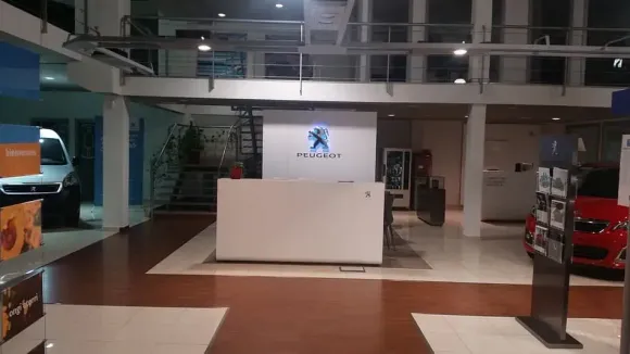 Un concesionario de coches con el logotipo de Peugeot en la pared.