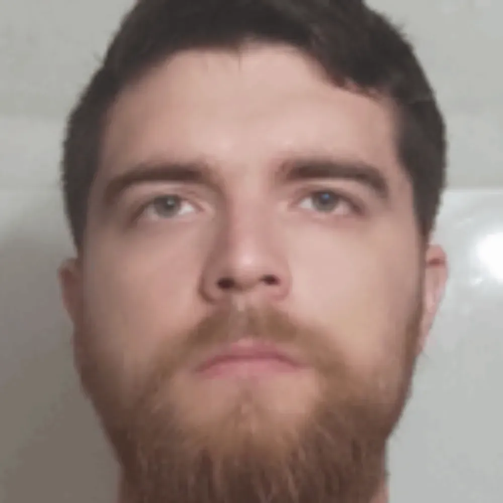 Primer plano de una persona con cabello oscuro, ojos marrones y barba tupida de color castaño claro