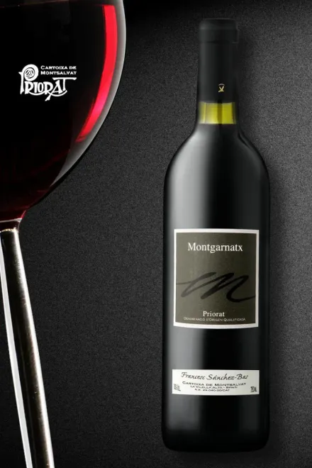 Una botella de vino tinto Muga junto a una copa de vino tinto parcialmente visible sobre un fondo oscuro y texturizado.