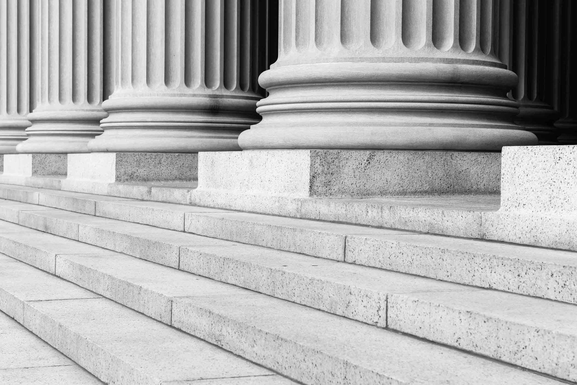 Una fotografía en blanco y negro de una fila de columnas y escaleras.