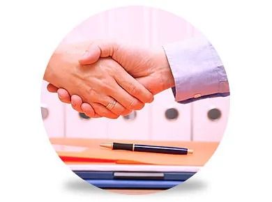 Dos personas se dan la mano sobre una mesa con un bolígrafo.