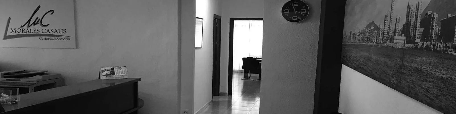Una fotografía en blanco y negro de un pasillo con un reloj en la pared.