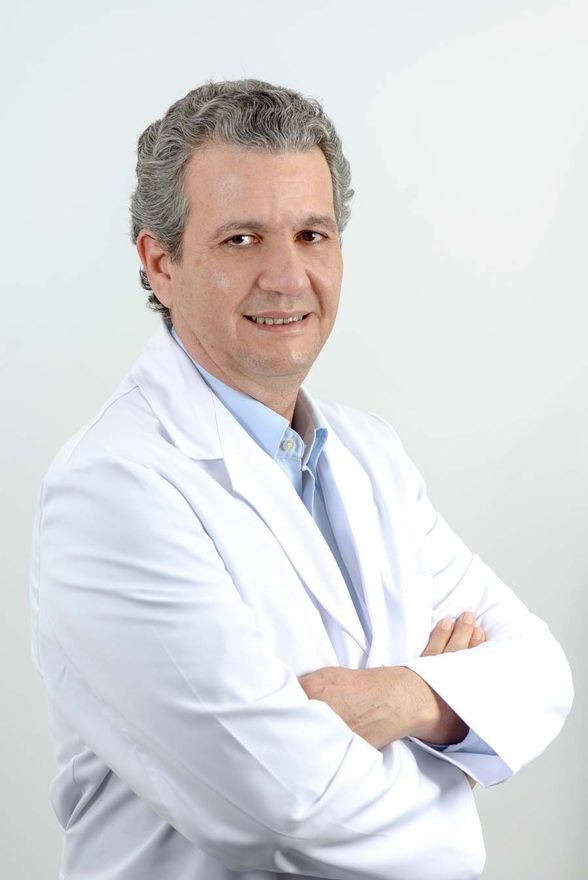 Un hombre con una bata blanca de laboratorio y los brazos cruzados.