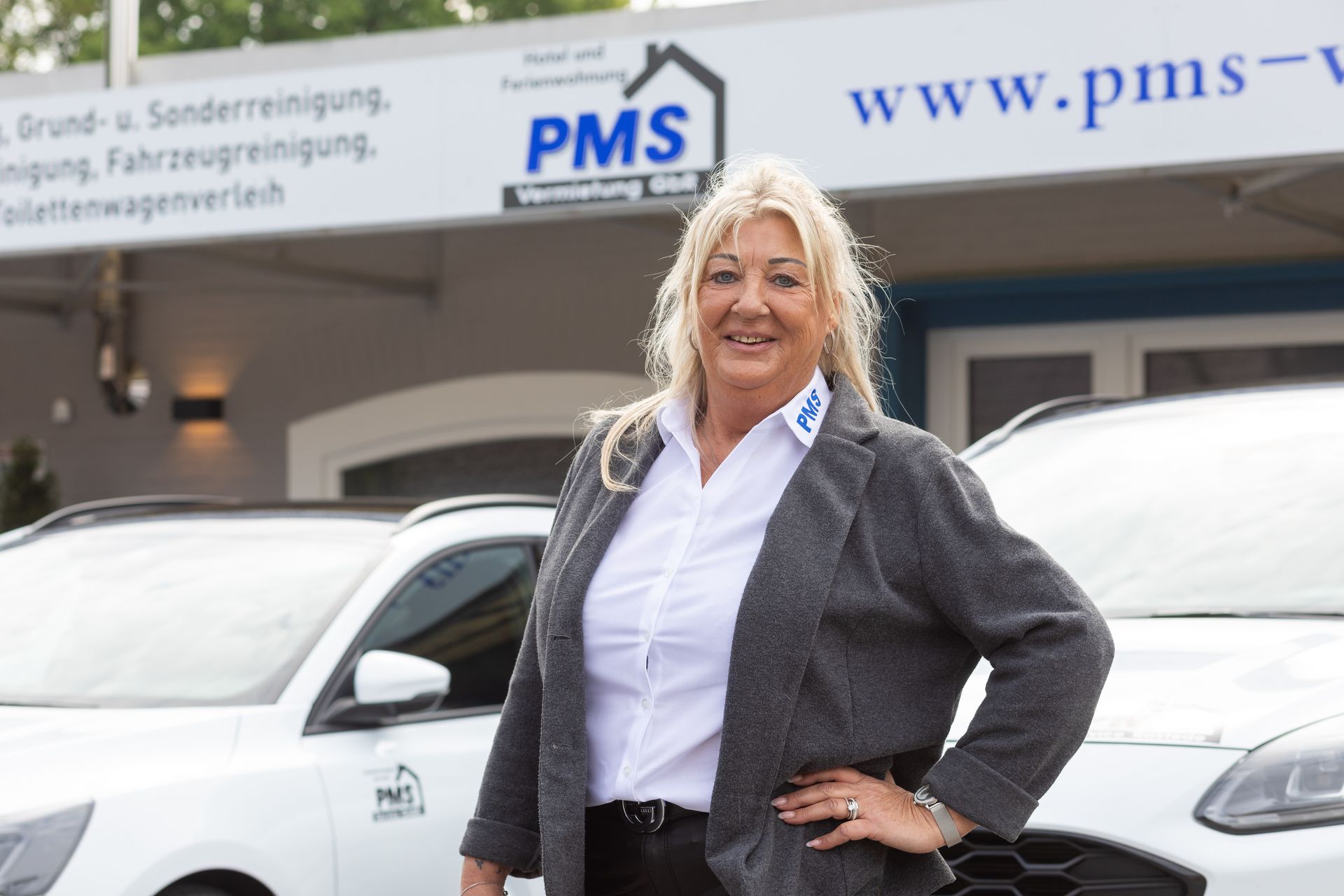 Eine Frau steht vor einem Gebäude mit einem Schild mit der Aufschrift PMS.