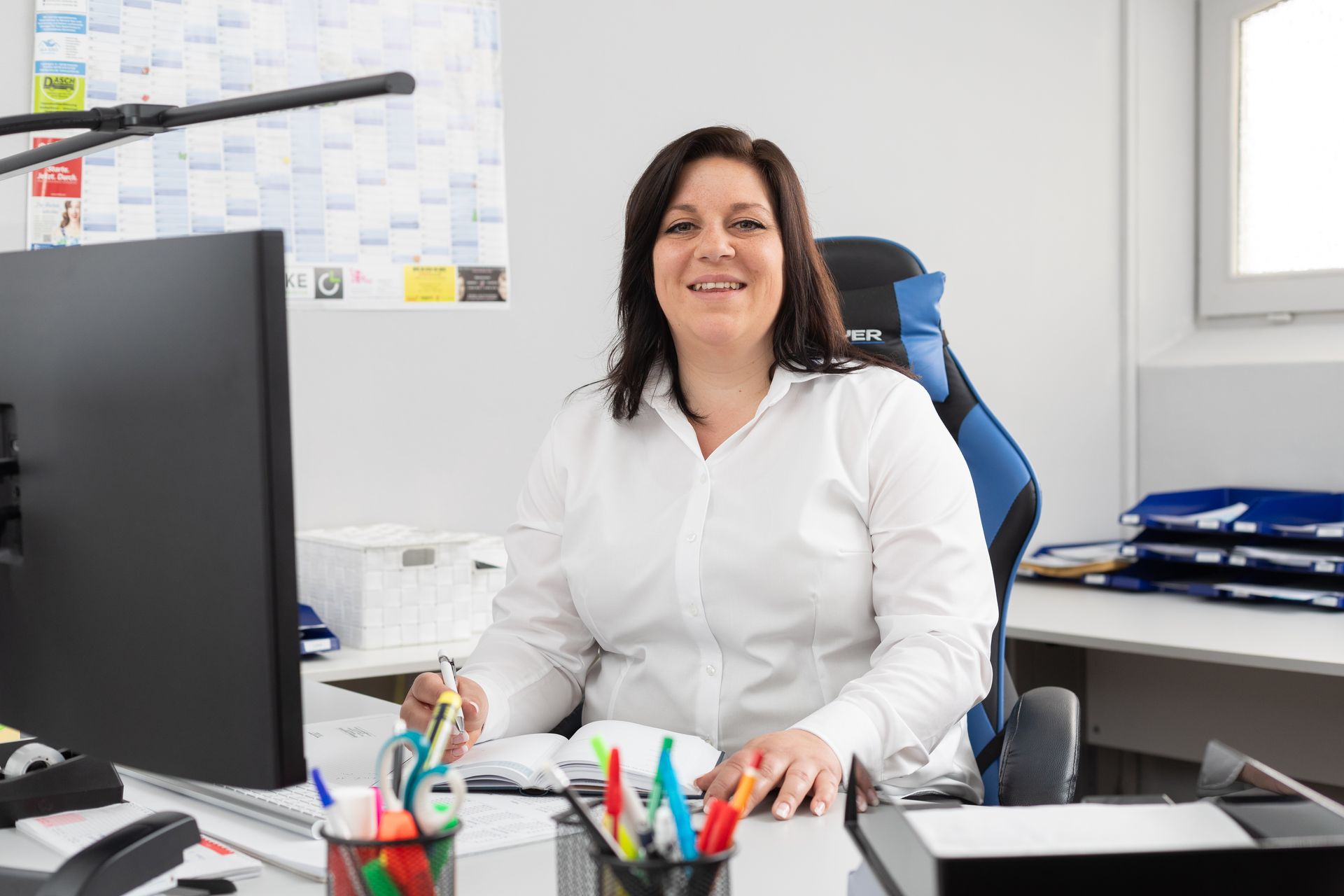 Eine Frau sitzt an einem Schreibtisch vor einem Computer.