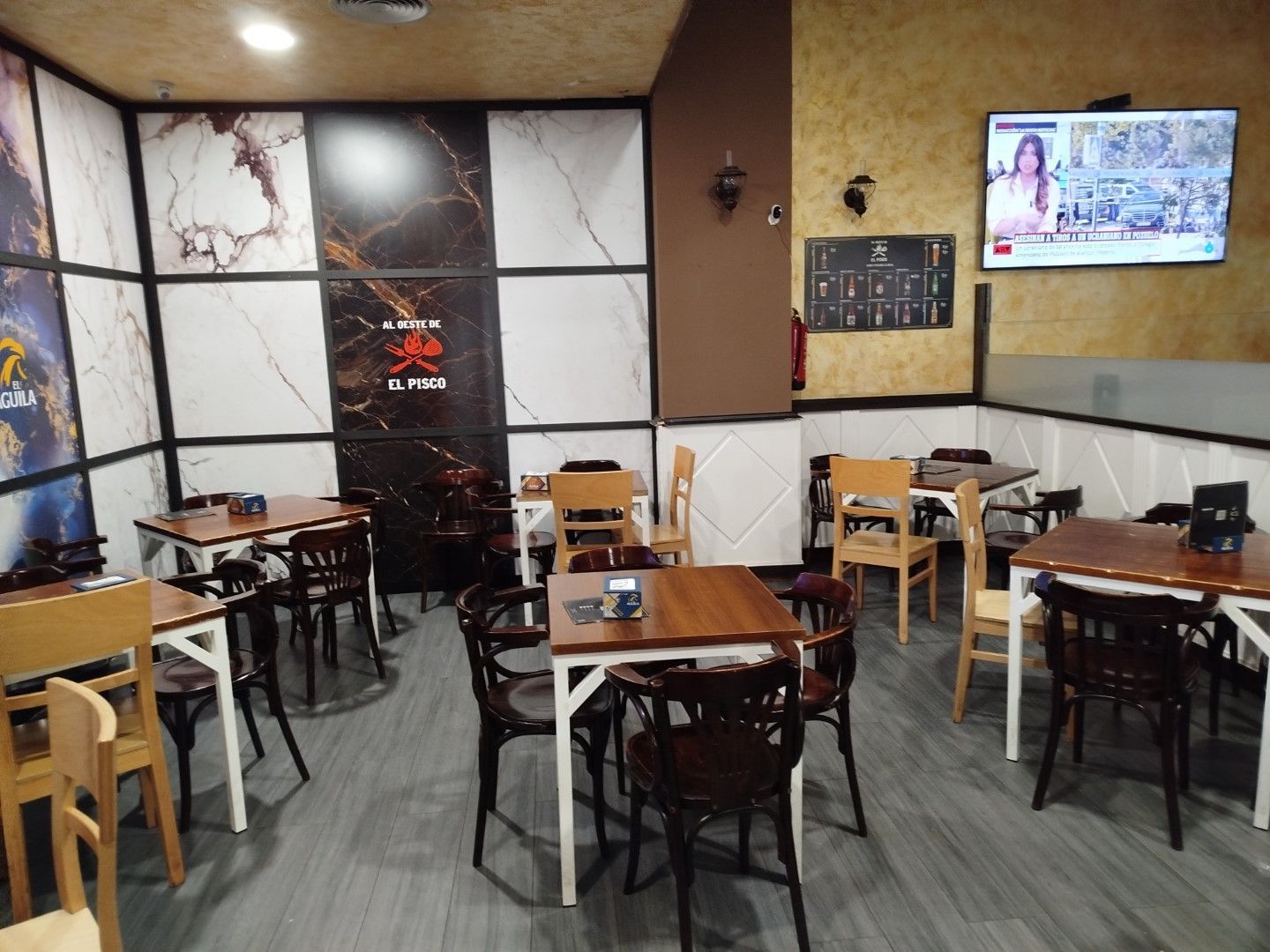 Un restaurante con mesas y sillas y un televisor en la pared.