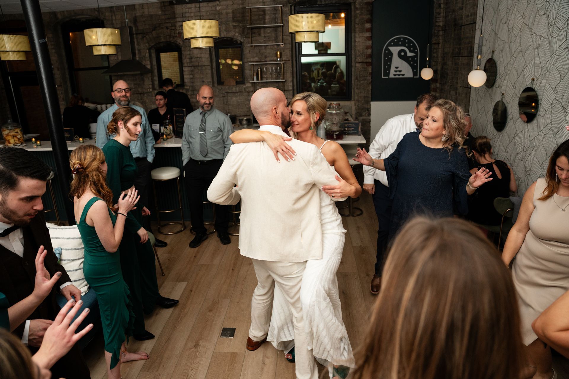 A bride and groom are dancing in front of a crowd of people at a wedding reception.
