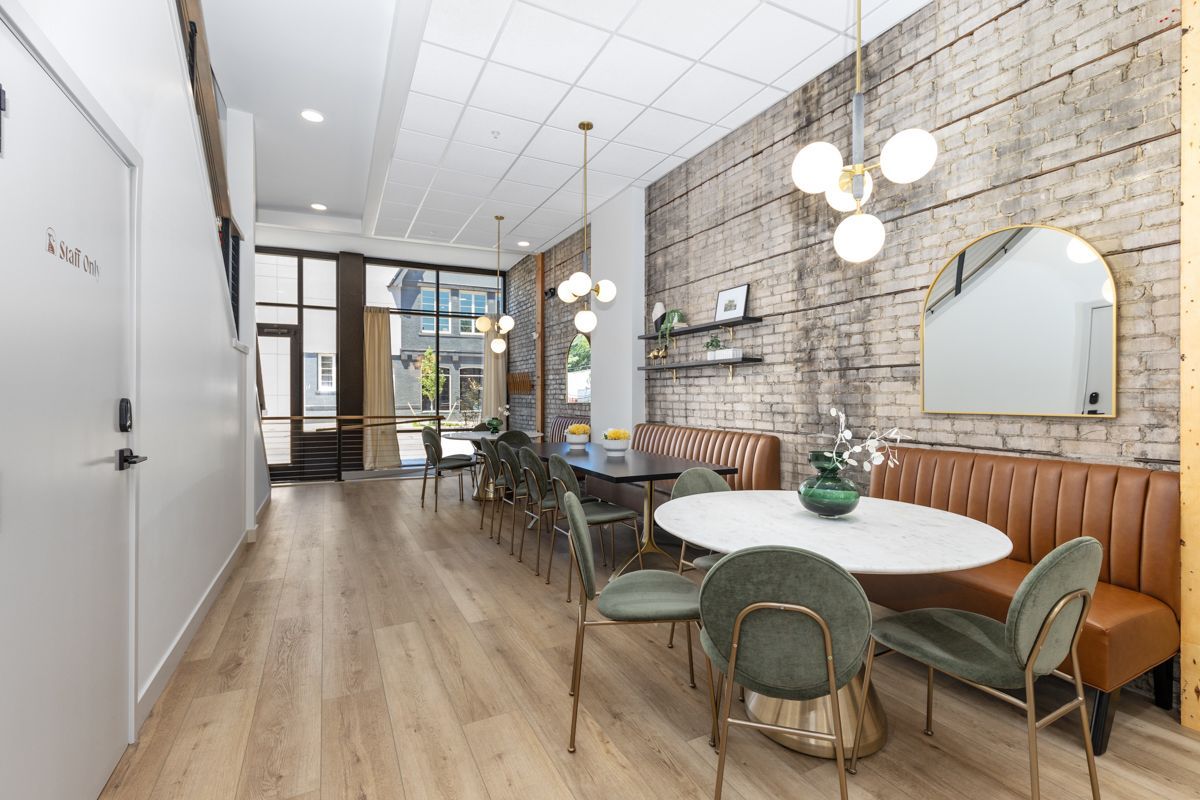 A large room with a table and chairs and a brick wall.