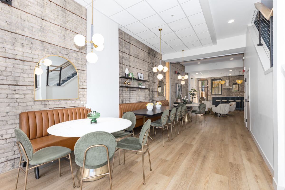 A large room with tables and chairs and a brick wall.