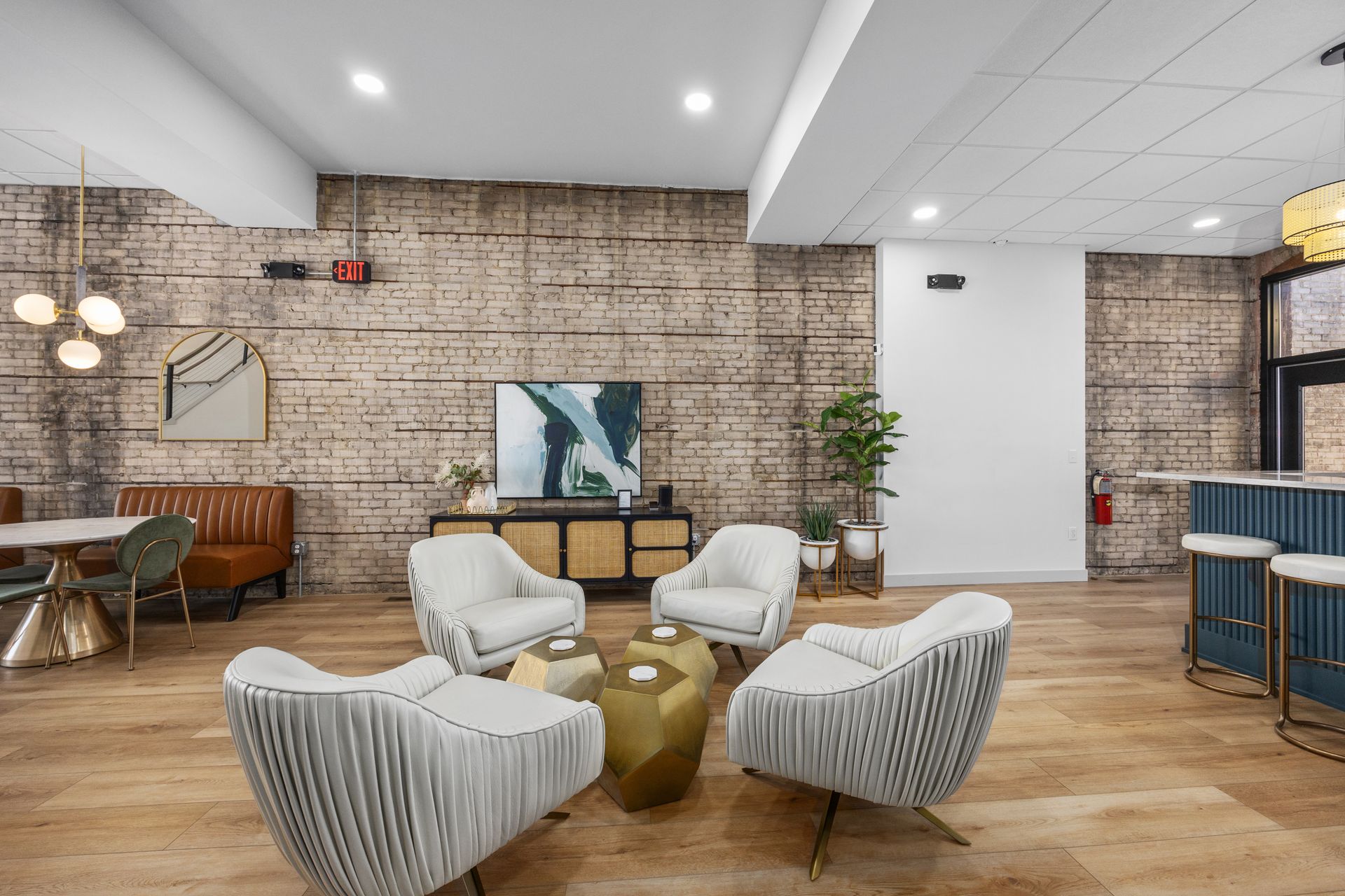 A living room with a brick wall , chairs , tables and a television.