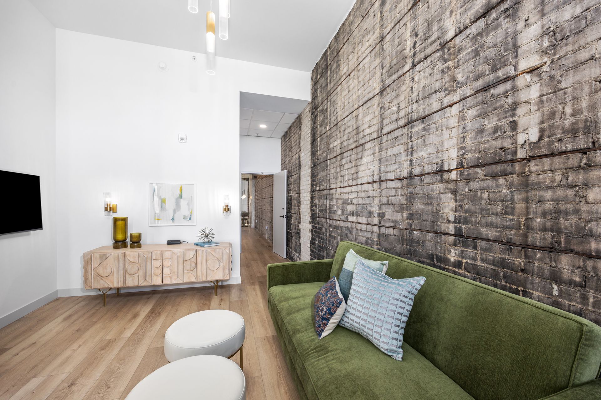 A living room with a green couch and a brick wall.