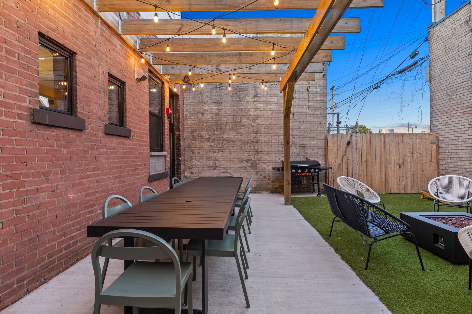 A patio with a long table and chairs under a pergola.