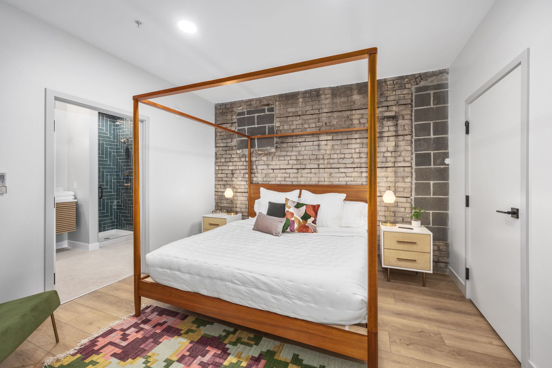 A bedroom with a four poster bed and a brick wall.