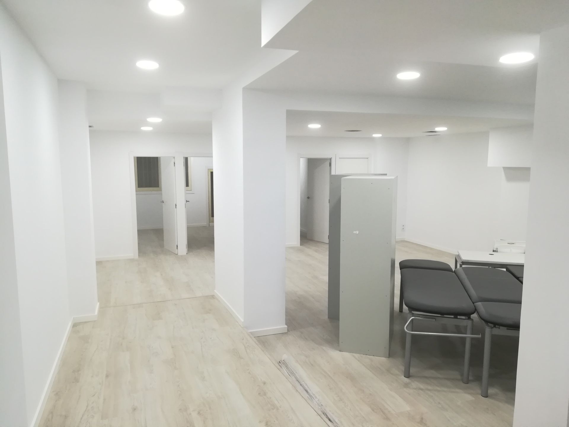 Amplio espacio de oficina vacío, con paredes blancas, luces empotradas y sillas junto a una mesa