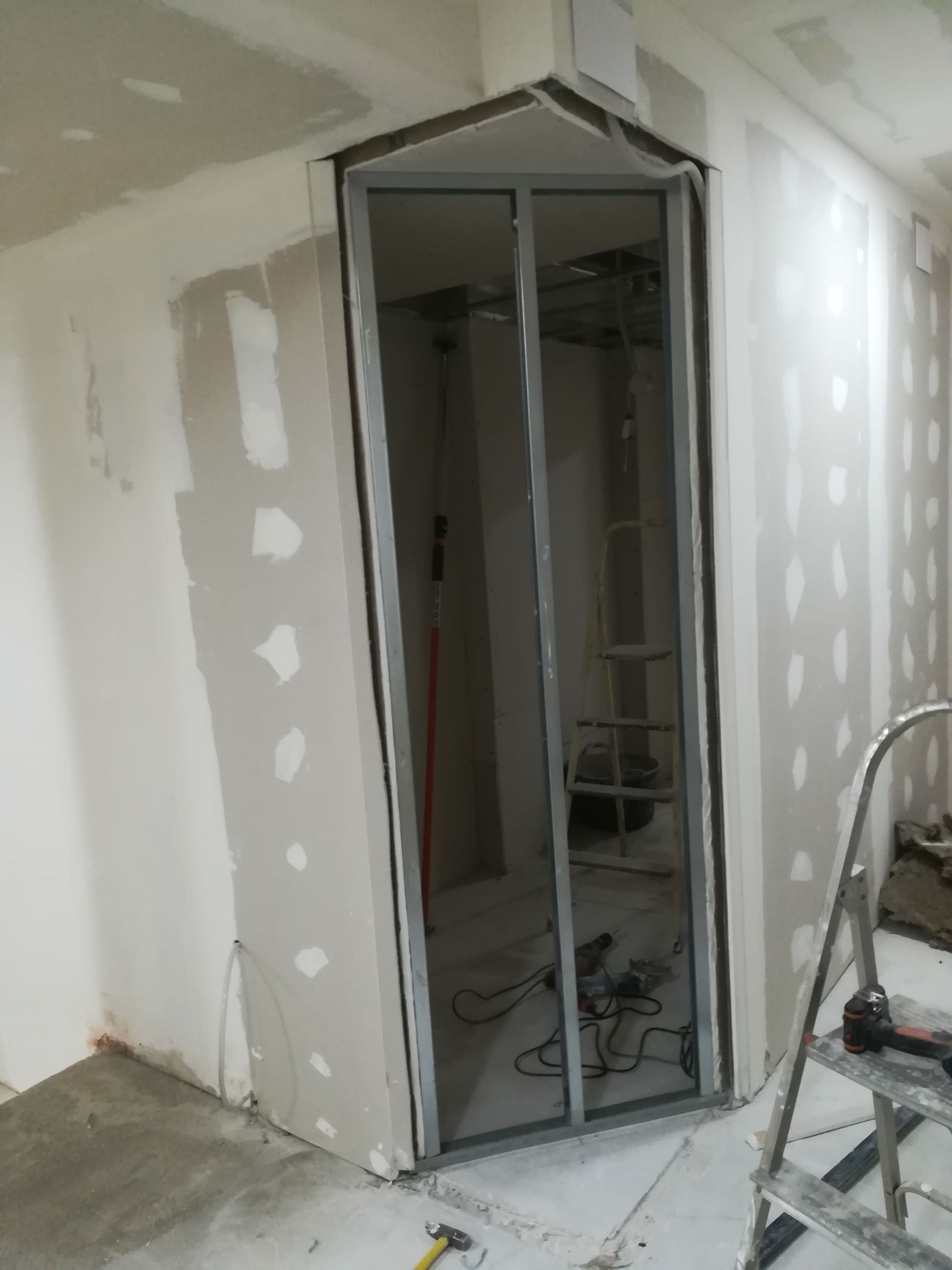 Habitación en obras con una puerta corredera de espejo parcialmente instalada en un hueco de pladur