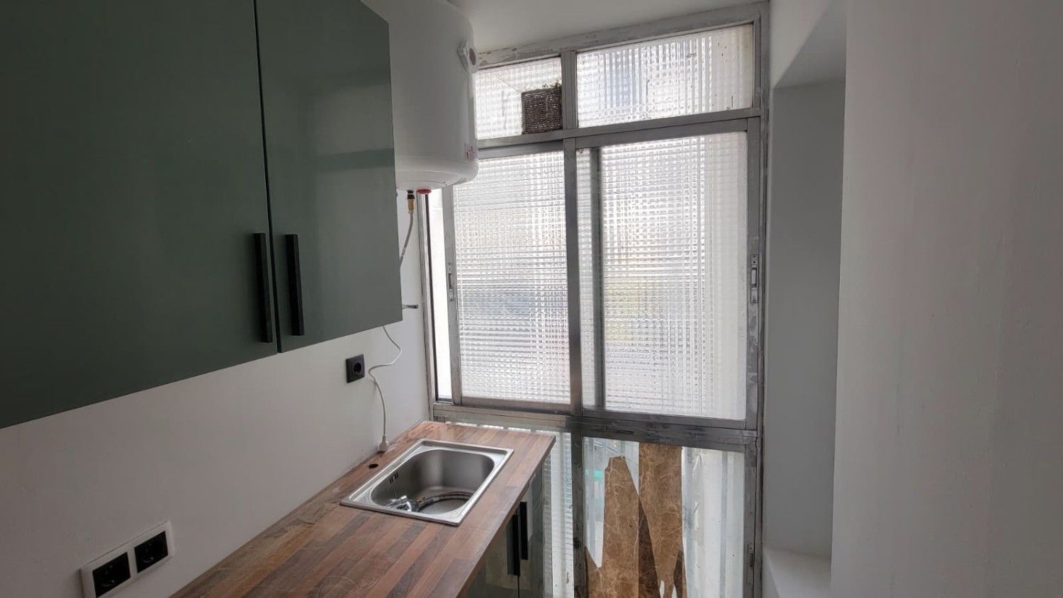 Cocina pequeña con encimera de madera, fregadero de acero inoxidable