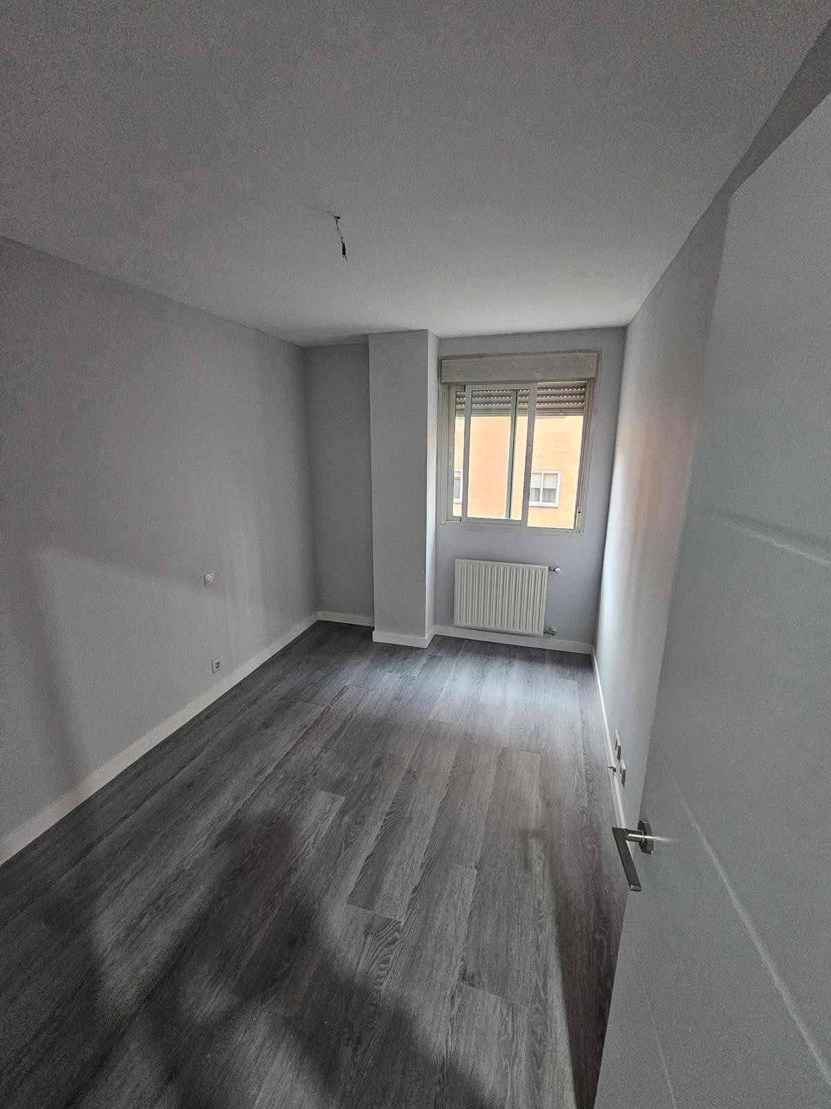 Persona que utiliza un destornillador para instalar un tomacorriente azul en una pared blanca.