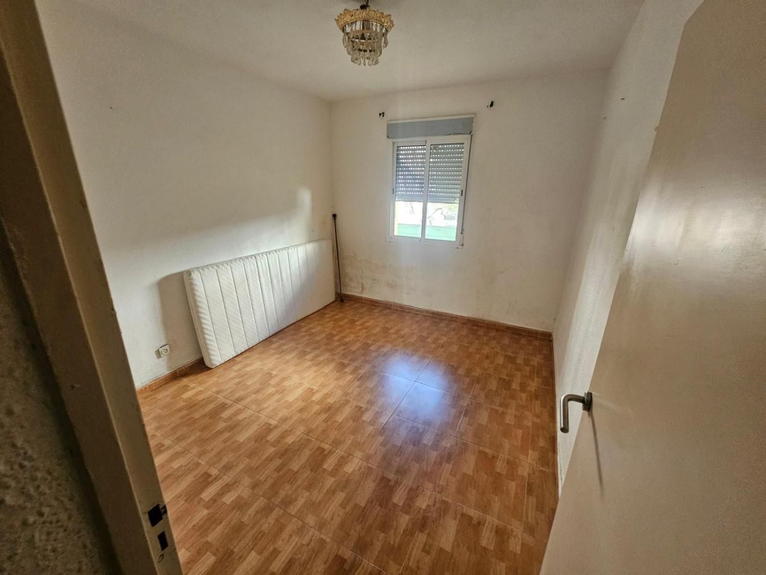 Un dormitorio vacío y soleado con suelo de madera clara