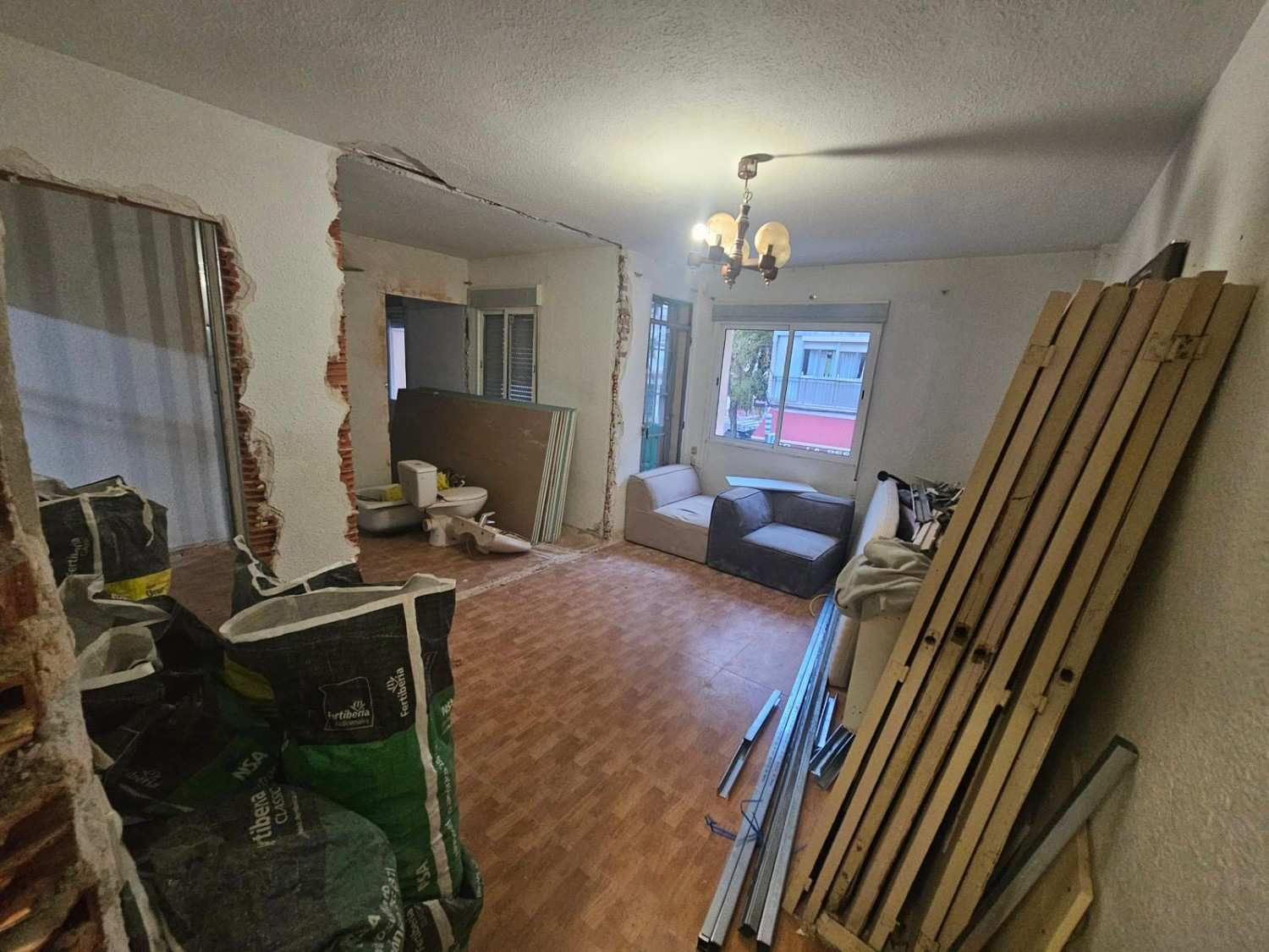 Una sala de estar en obras de renovación con secciones de pared rotas