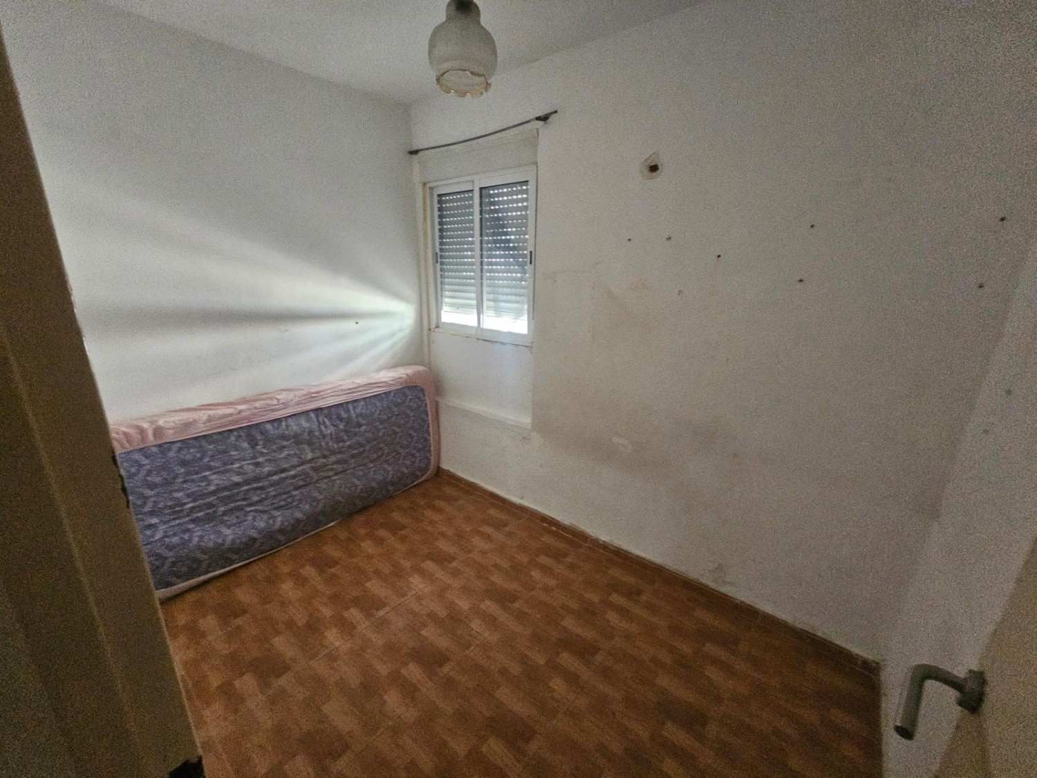 Un dormitorio vacío con paredes blancas, suelo con diseño de madera