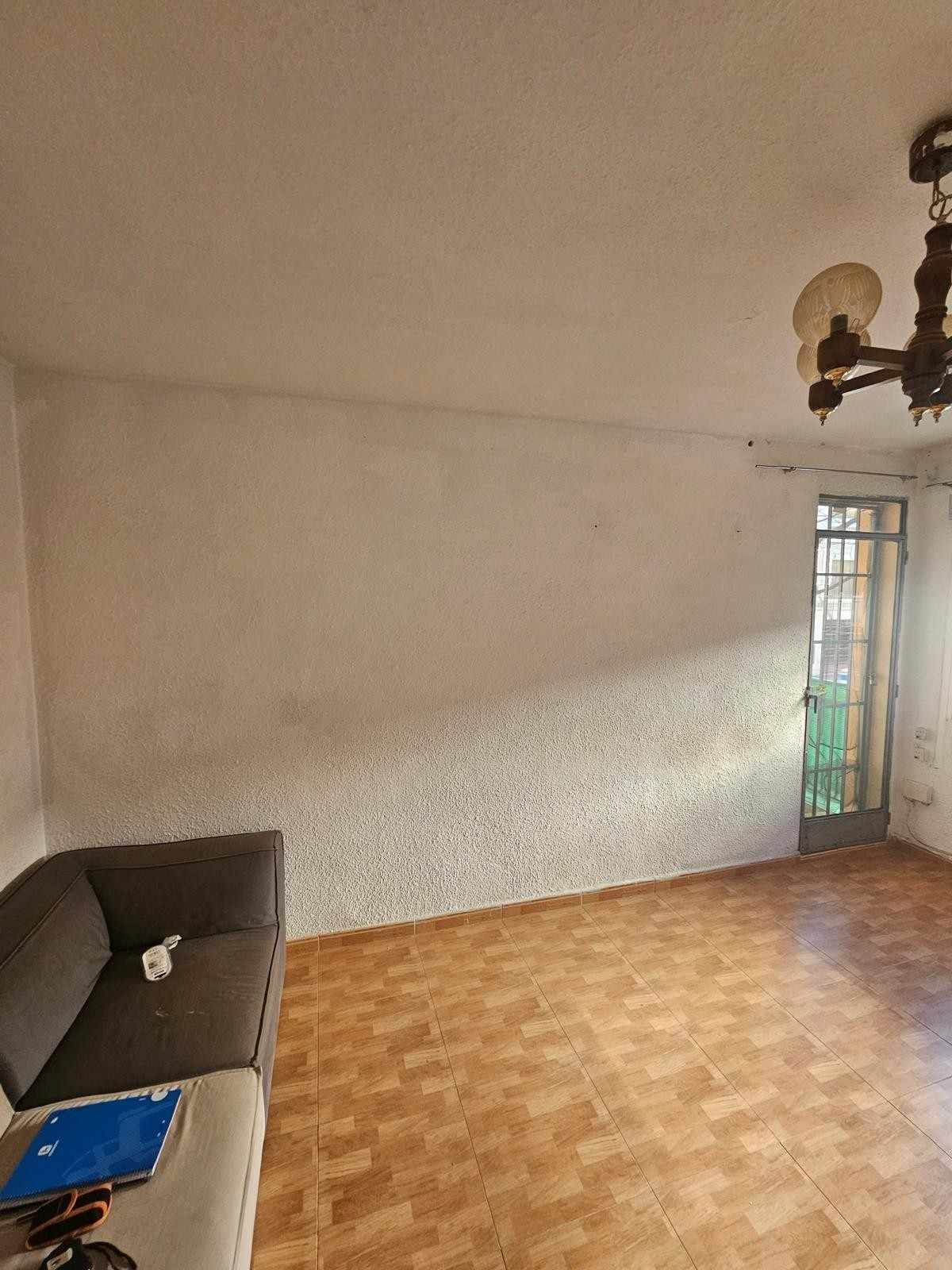 Una habitación vacía con un sofá gris oscuro, suelo de madera clara