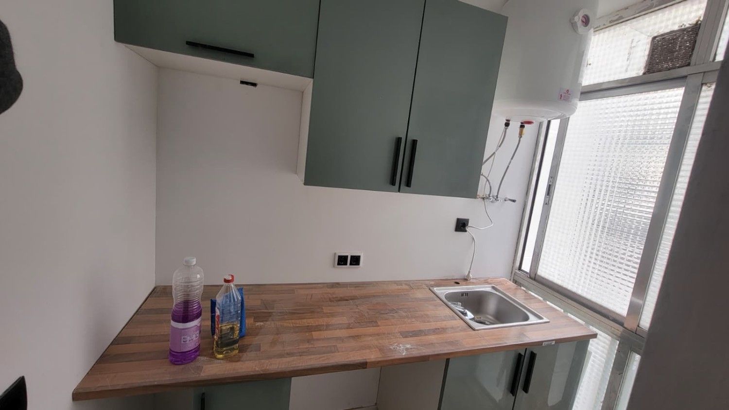 Un rincón de cocina con armarios de color verde salvia