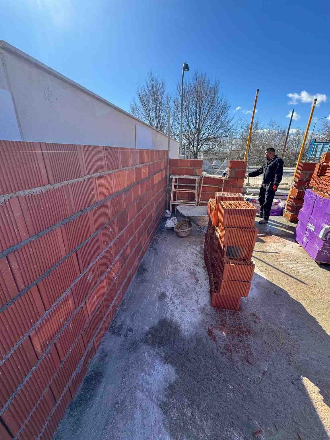Materiales de pintura colocados contra una pared blanca: escalera, rodillo, tela protectora y lata de pintura.