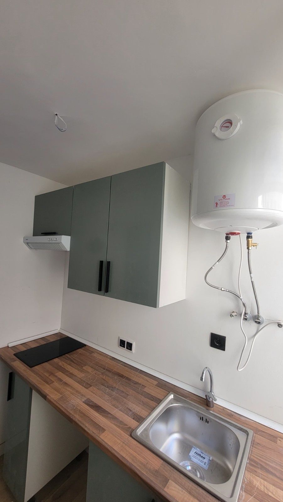 Una zona de cocina con armarios grises, encimera de madera