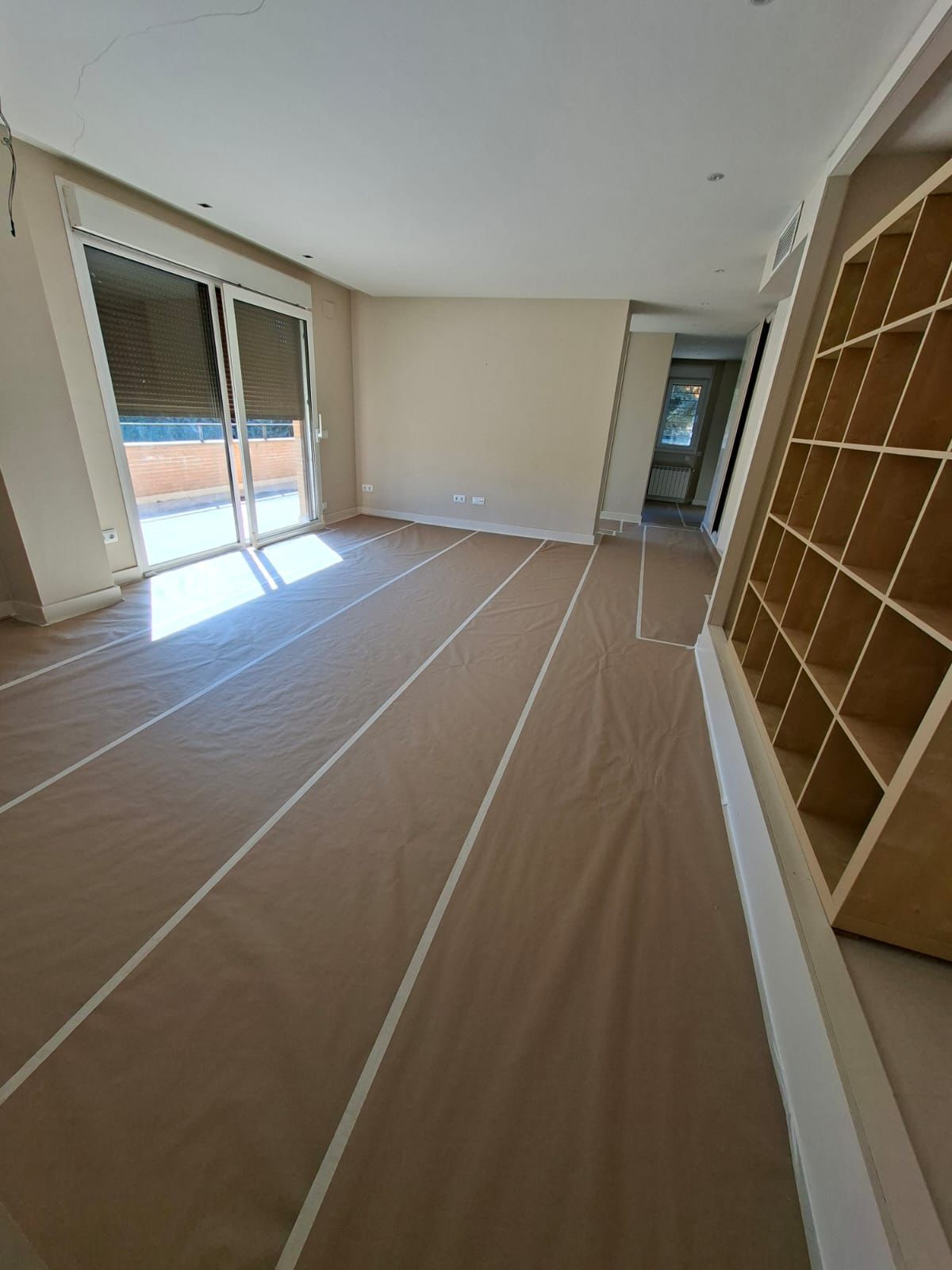 Persona que sostiene un taladro eléctrico de color verde azulado, vistiendo un delantal oscuro y con las manos polvorientas.