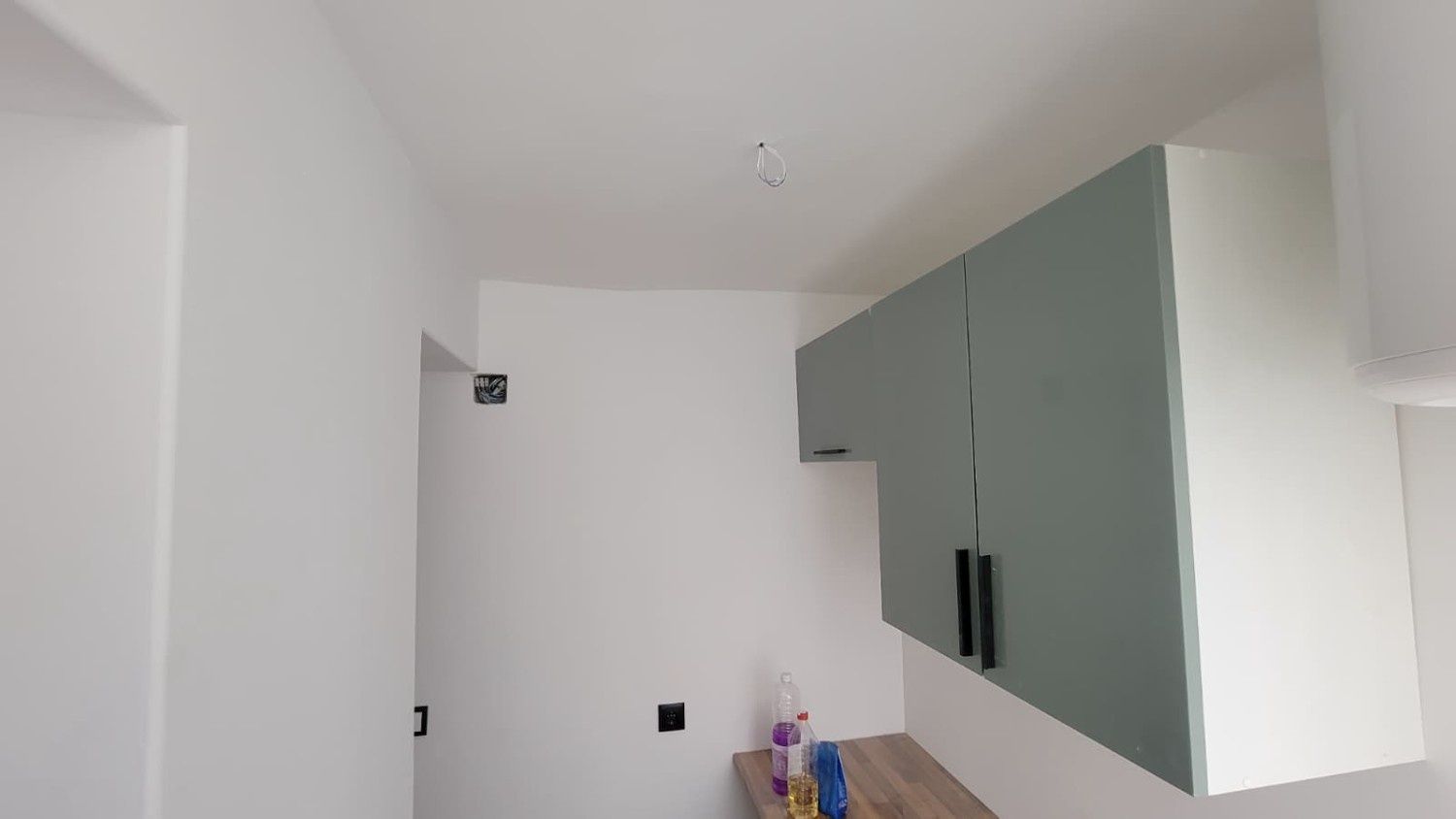 Vista de una cocina con armarios superiores de color verde salvia