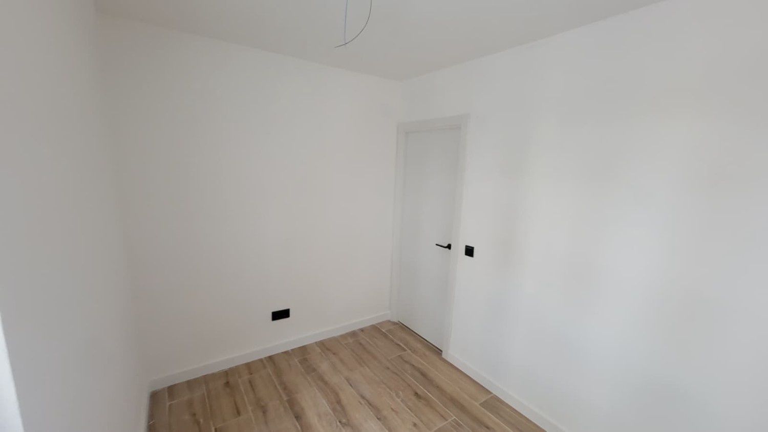 Una habitación pequeña y vacía con paredes blancas lisas