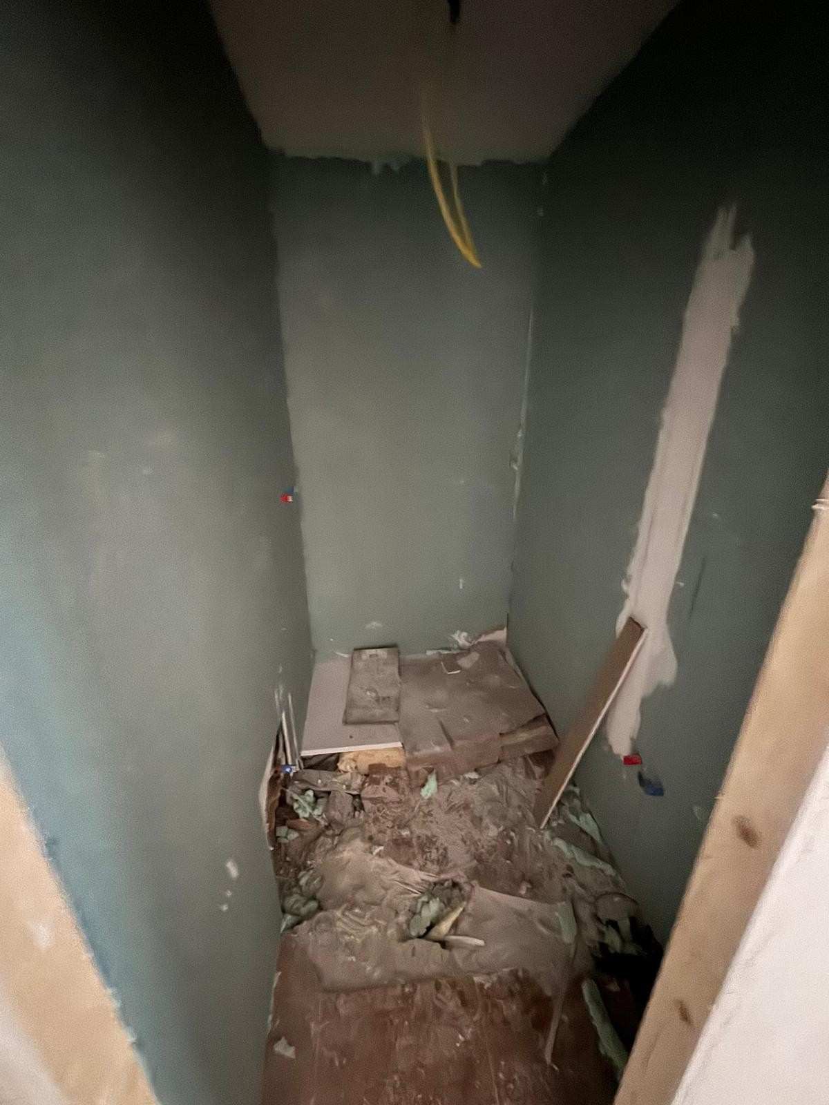 Una habitación interior estrecha y sin terminar, con paredes verdes