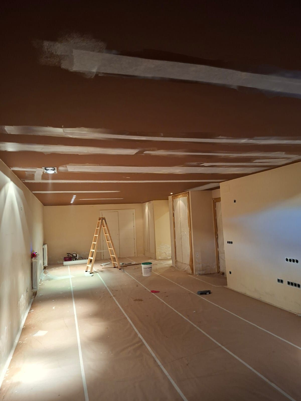 Una persona con camisa blanca y gafas utiliza una batidora en una obra en construcción.