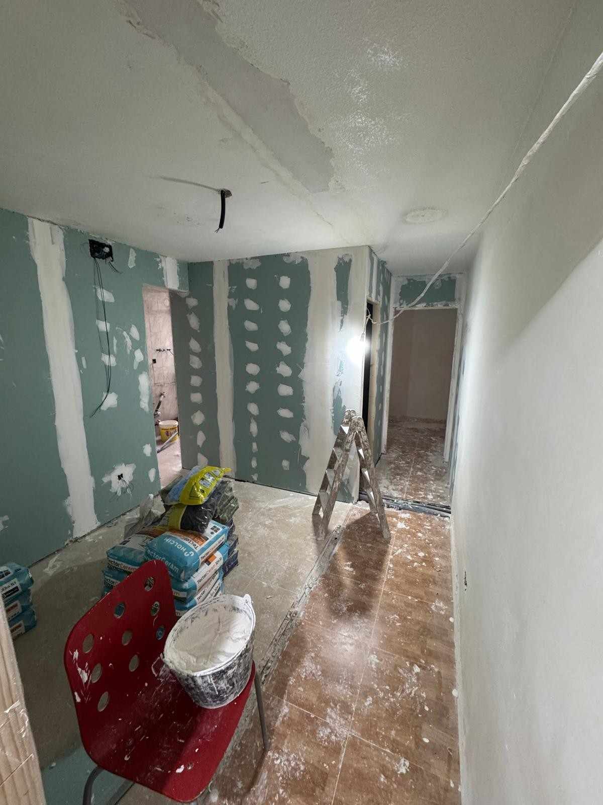 Una persona agachada en el alféizar de una ventana, trabajando en el marco.