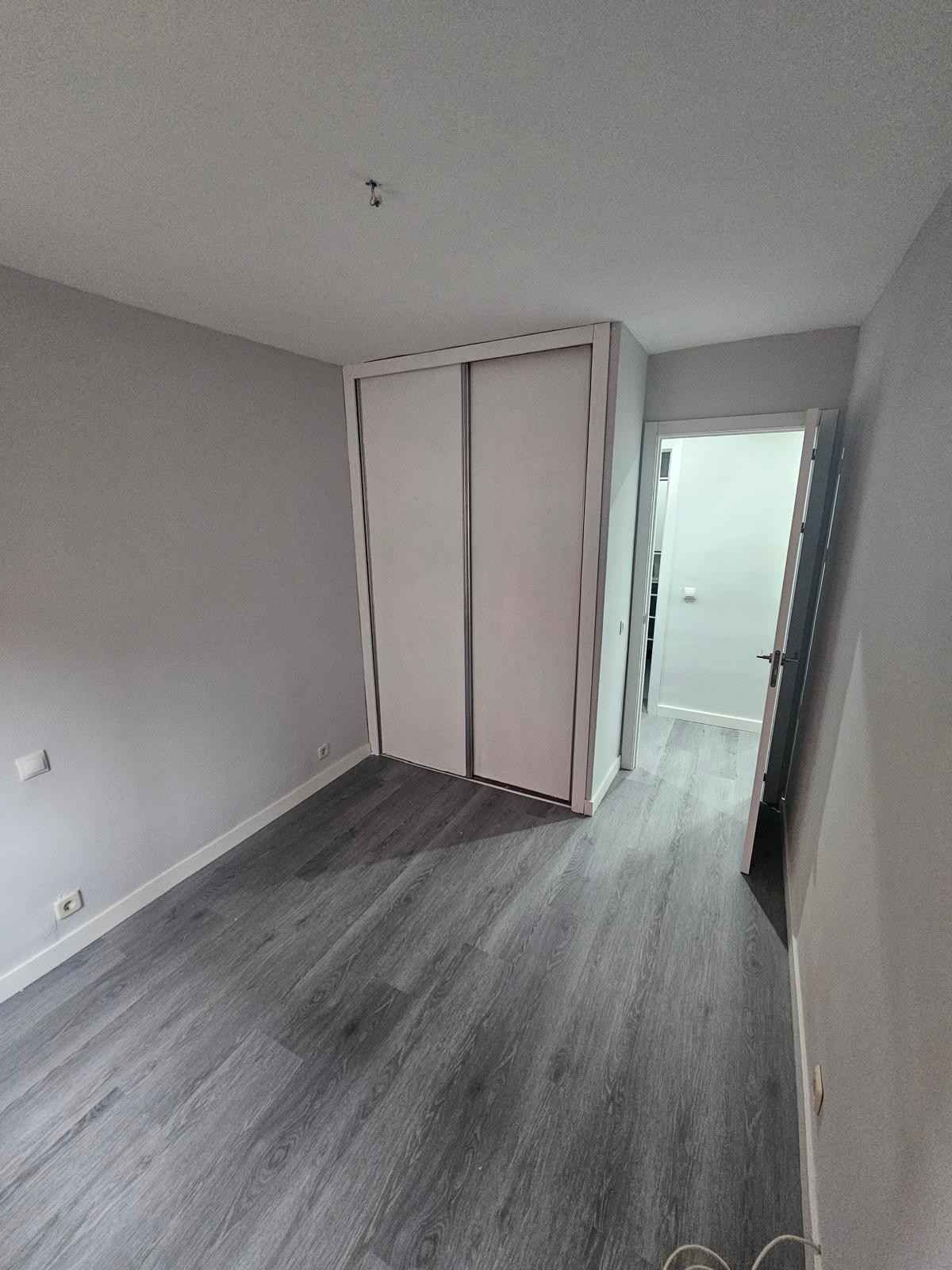 Persona con casco examinando una tableta en una habitación en construcción, con herramientas y una luz de trabajo.