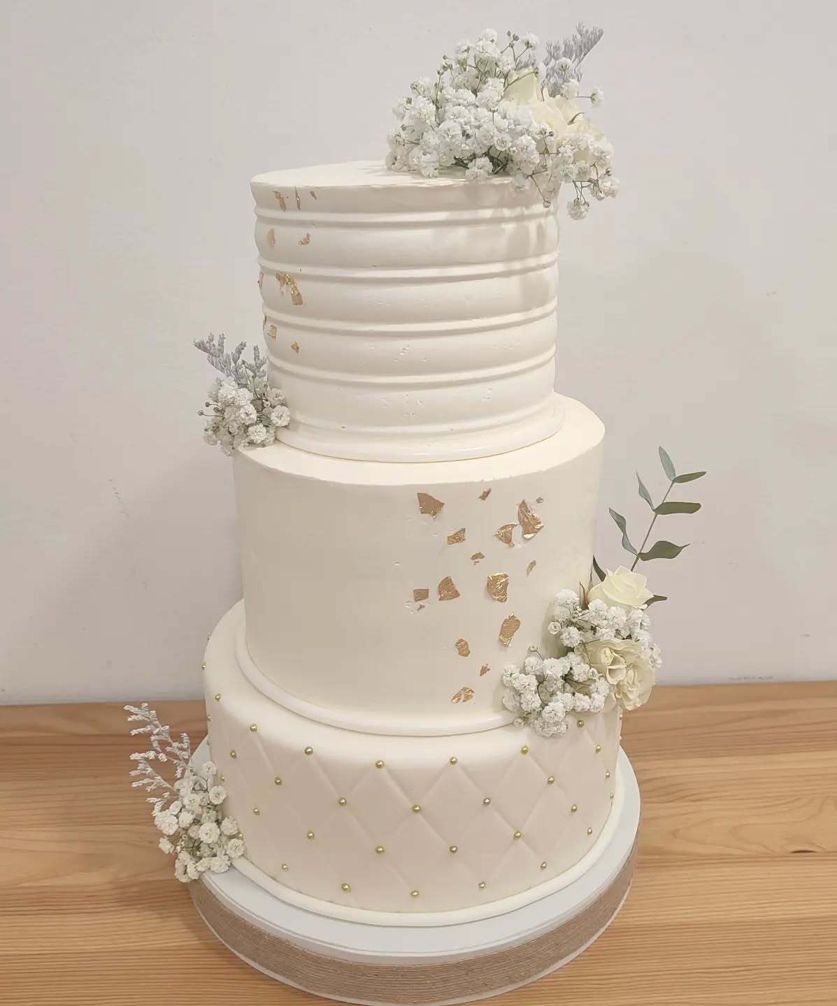 Un pastel de bodas blanco reposa sobre una mesa de madera.