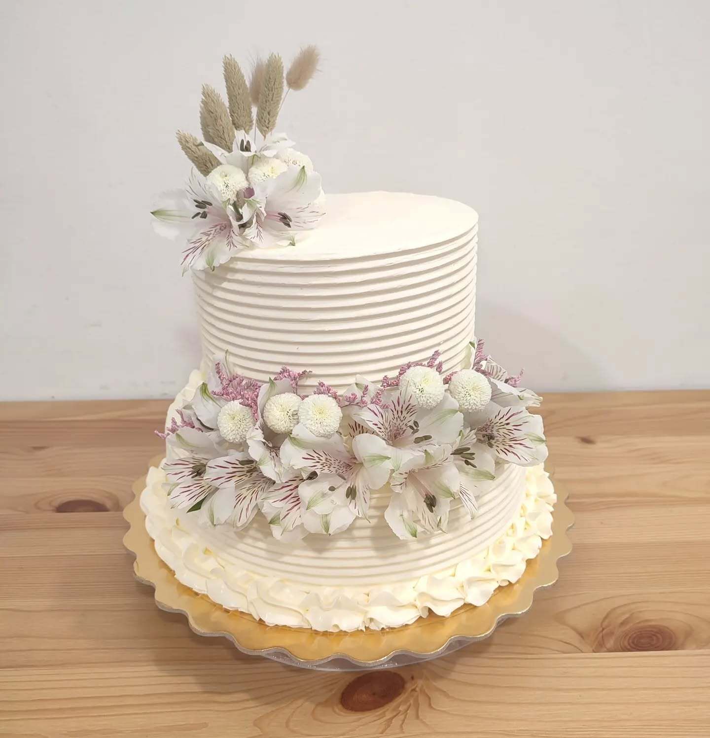 Un pastel blanco con flores encima está sobre una mesa de madera.