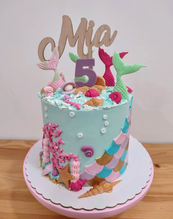 Un pastel con temática de sirena con el número 5 en la parte superior.
