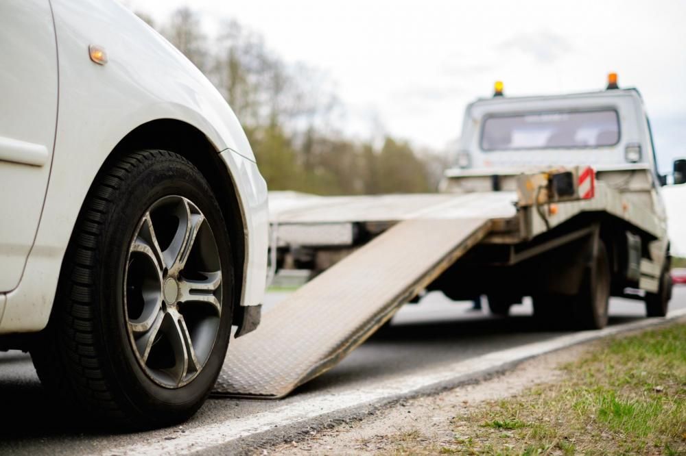 Une dépanneuse charge une voiture blanche sur un plateau en bord de route