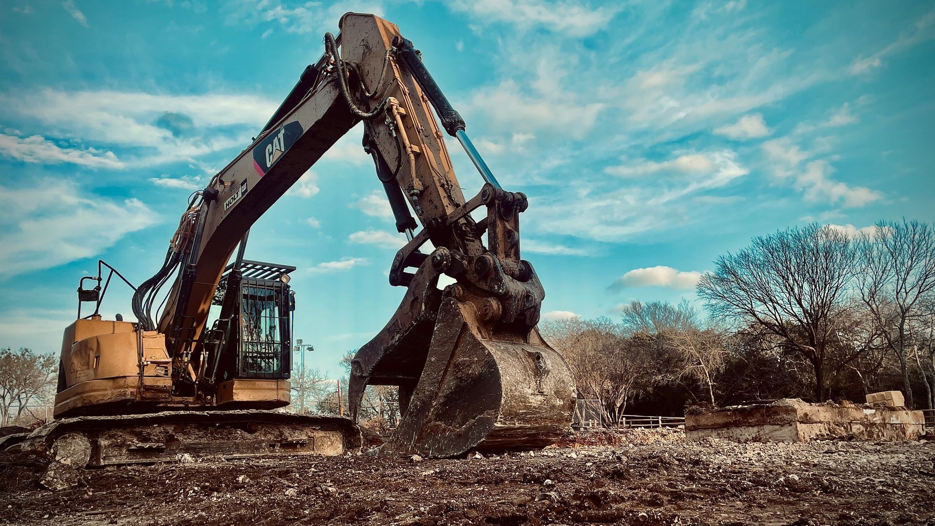 Gelber LKW mit rotem Kran und Greiferaufsatz vor einem weißen Gebäude.