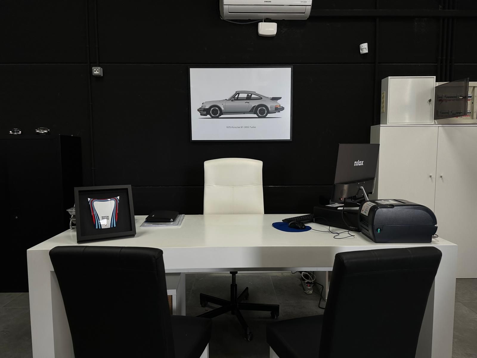 Un escritorio blanco con una imagen de un automóvil en la pared encima.
