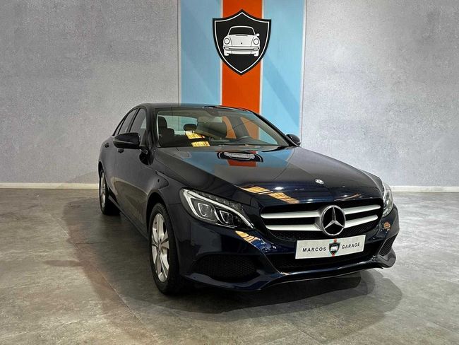 Un Mercedes Benz Clase C azul está estacionado en una sala de exposición.