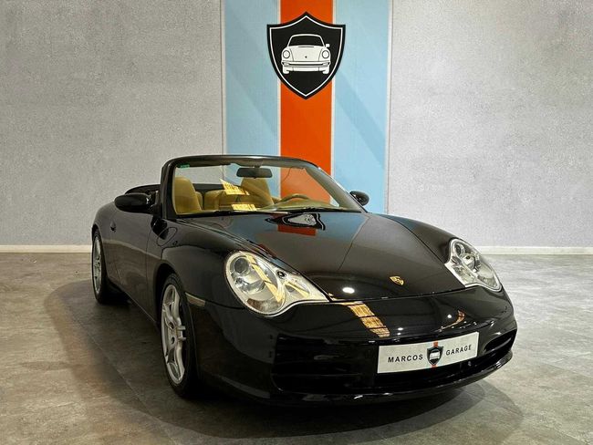 Un Porsche 911 Cabriolet negro está estacionado frente a una pared de rayas azules y naranjas.