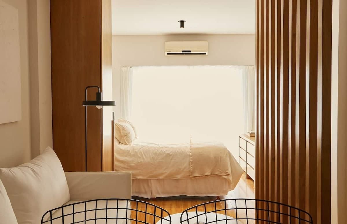 Un moderno estudio tipo apartamento que cuenta con un juego de comedor de madera, una cocina compacta con gabinetes de madera clara y pisos de madera noble.
