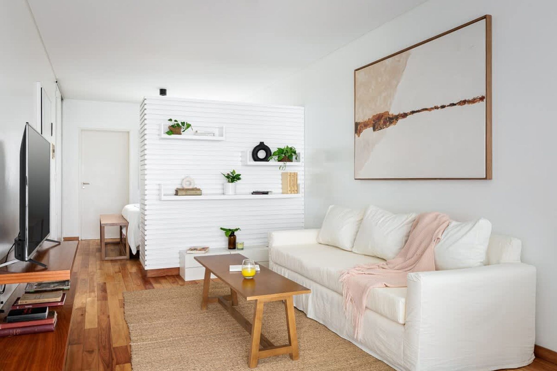 Un moderno estudio tipo apartamento que cuenta con un juego de comedor de madera, una cocina compacta con gabinetes de madera clara y pisos de madera noble.